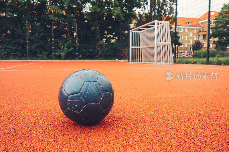 橙色地面上的蓝色足球，背景是足球球门