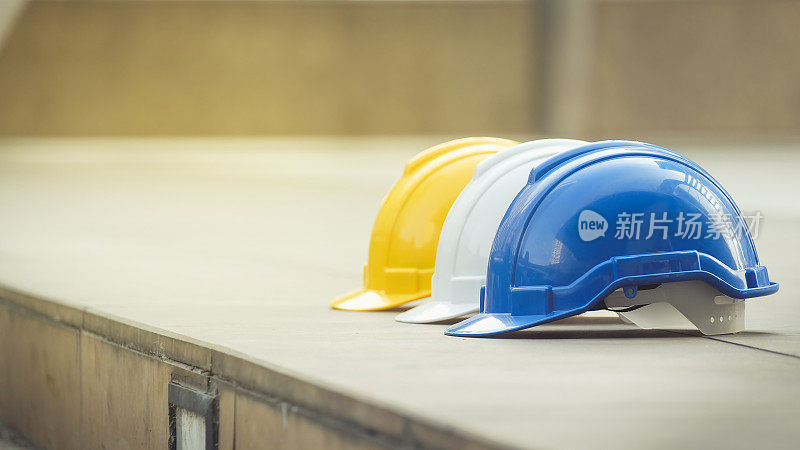 城市混凝土地面上工程师或工人安全工程用白色、黄色、蓝色硬质安全帽