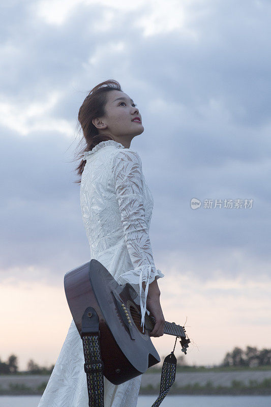 背着吉他的漂亮女人在天空中行走