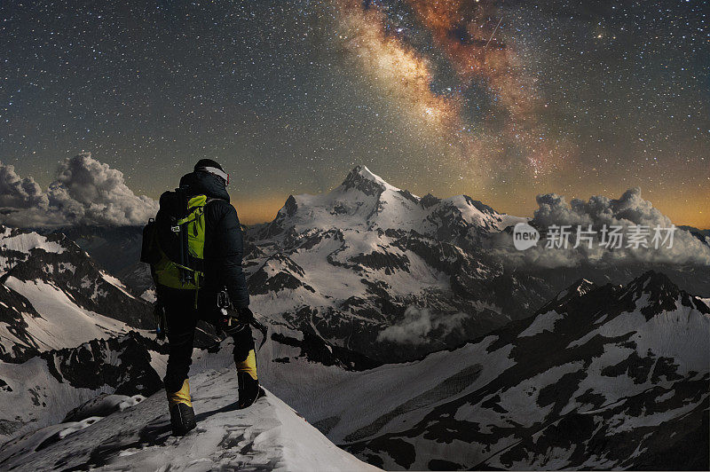 夜晚的照片登山者站在山顶的雪山，看着周围的山，星空和银河