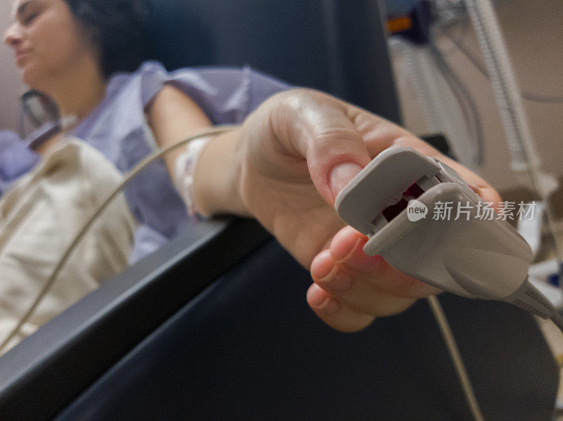 脉搏血氧计-血氧水平测量装置-附着在术后镇静的妇女的手指上。