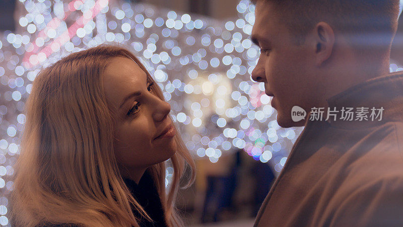 一对年轻夫妇在圣诞霓虹灯下深情地望着对方