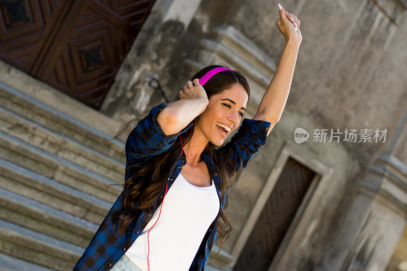 漂亮女孩戴着耳机在街上听音乐