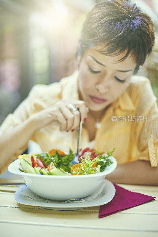 年轻漂亮的女人在餐厅吃地中海食物