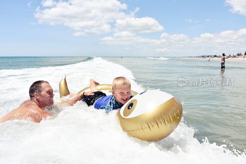 父亲帮助孩子在海滩上漂浮