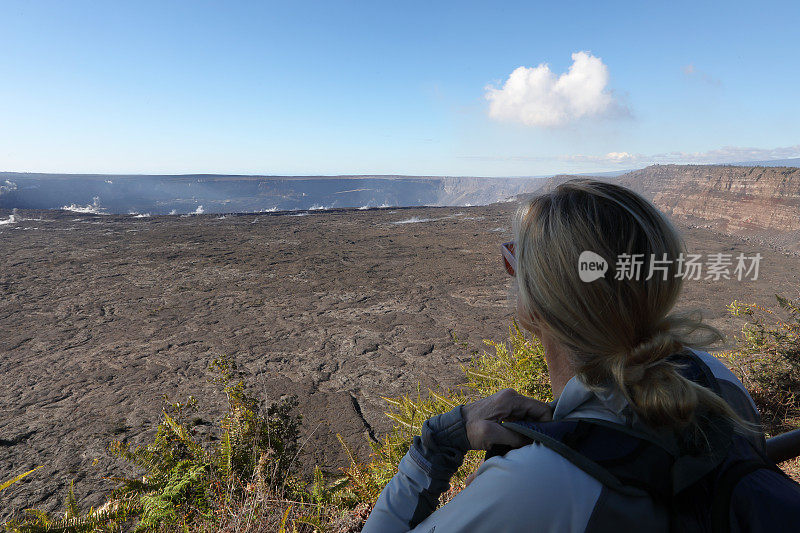 一名女性徒步旅行者眺望远处的火山熔岩