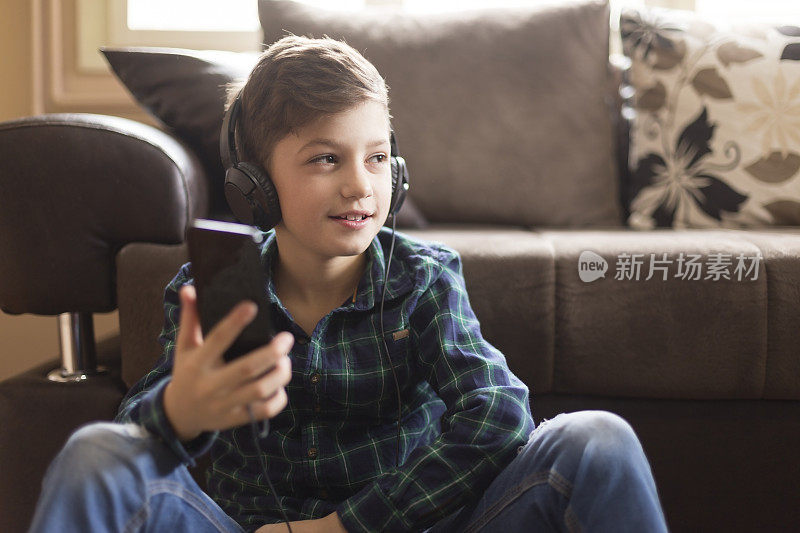 小男孩在家里戴着耳机听音乐