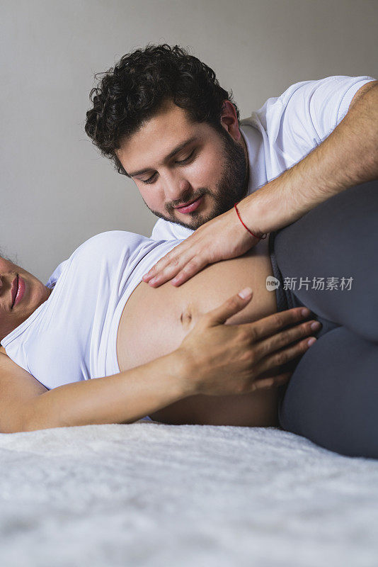 男人抚摸着妻子怀孕的腹部