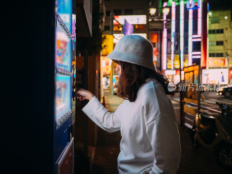 亚洲女人选择一些饮料在自动售货机