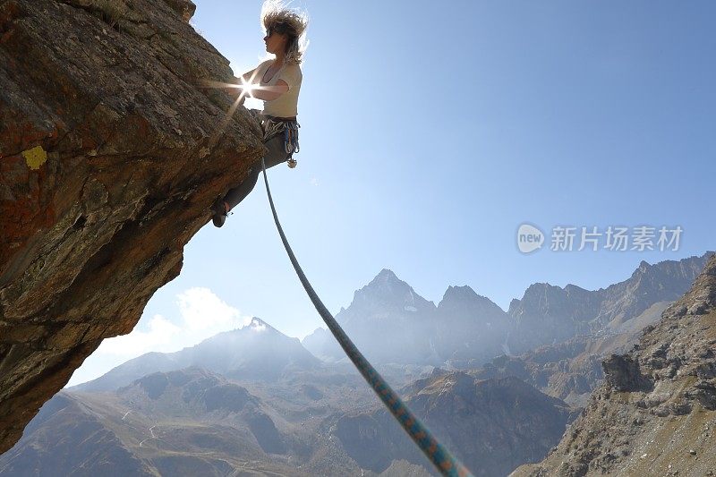 日出时，女性攀登者攀登悬岩峭壁