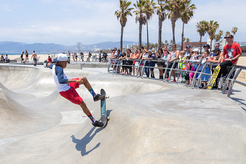 滑板男孩在加州洛杉矶威尼斯海滩的滑板公园练习。威尼斯海滩是洛杉矶最受欢迎的海滩之一