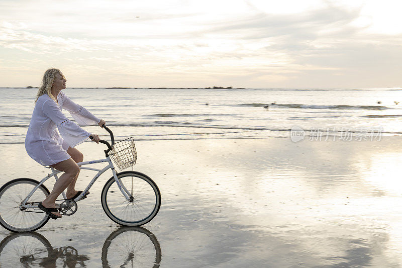 日出时分，一名女子骑着自行车沿着海滩骑行