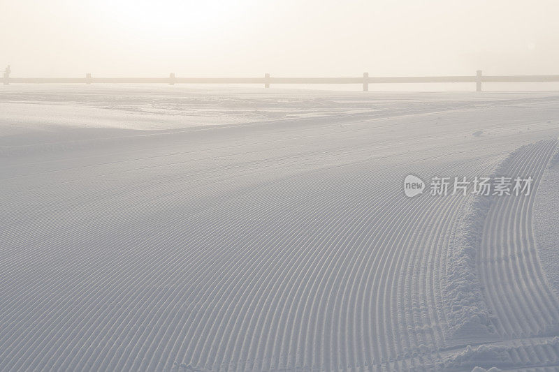 在一月的一个多雾的日子里，挪威的哈弗杰尔滑雪场的滑雪坡道被背光照亮