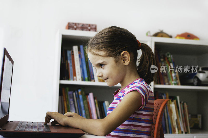 可爱的女孩使用笔记本电脑。玩视频游戏。做家庭作业。家庭生活