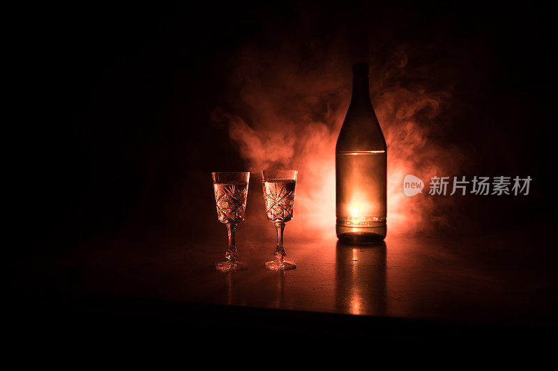 两杯伏特加与瓶在黑暗雾俱乐部风格的背景与发光灯(激光，Stobe)多颜色。会所饮品主题装饰。空的空间