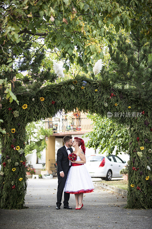 新娘和新郎在前院传统祭坛下接吻。