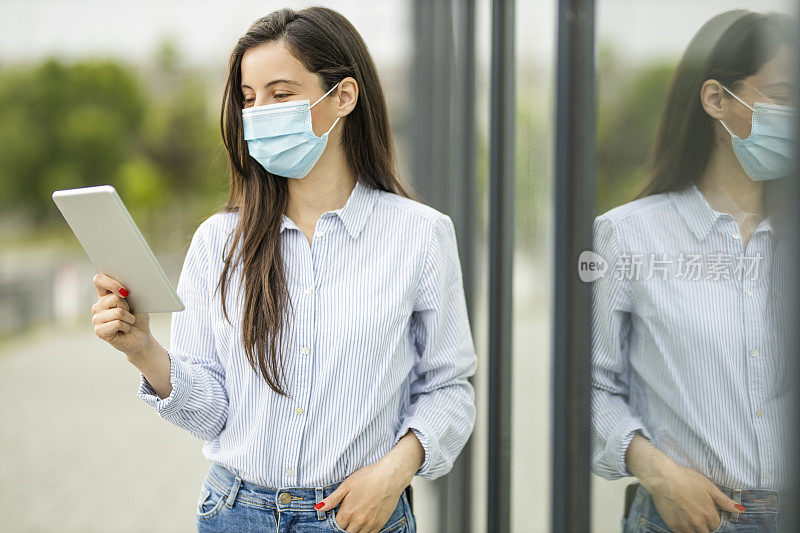 妇女戴着保护面罩，使用数码平板电脑