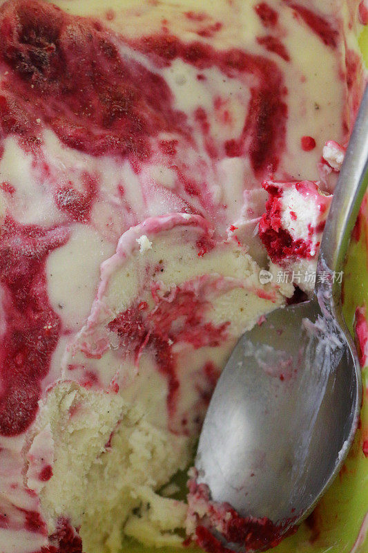 这是一碗自制的覆盆子冰淇淋，用金属勺子做成的红白相间的漩涡状冰冻甜点