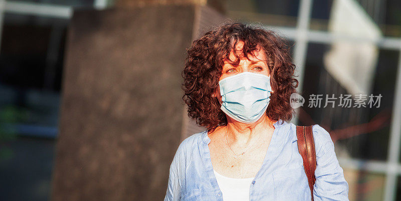 2019冠状病毒疫情期间，担心的戴面罩的妇女在户外行走