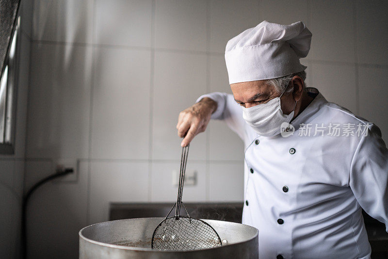 高级厨师在一个工业厨房里准备油炸食品