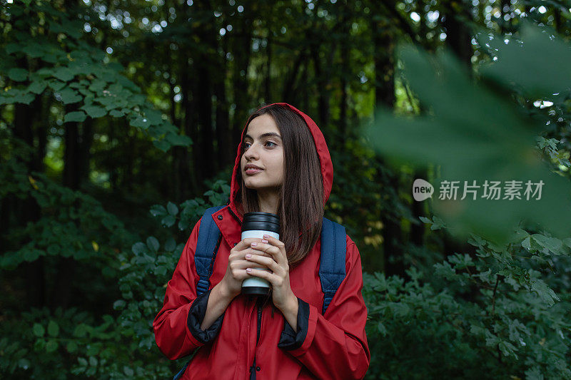穿着红色雨衣的年轻女子在大自然中徒步旅行
