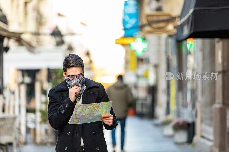 年轻人手里拿着地图，在城市里找路。