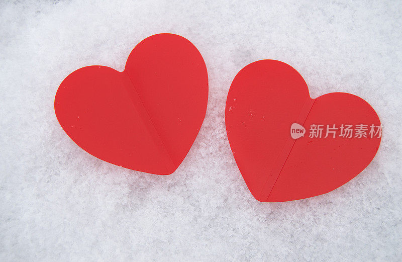 白雪皑皑的背景上，两颗美丽浪漫的红心在一起。爱情和情人节的概念