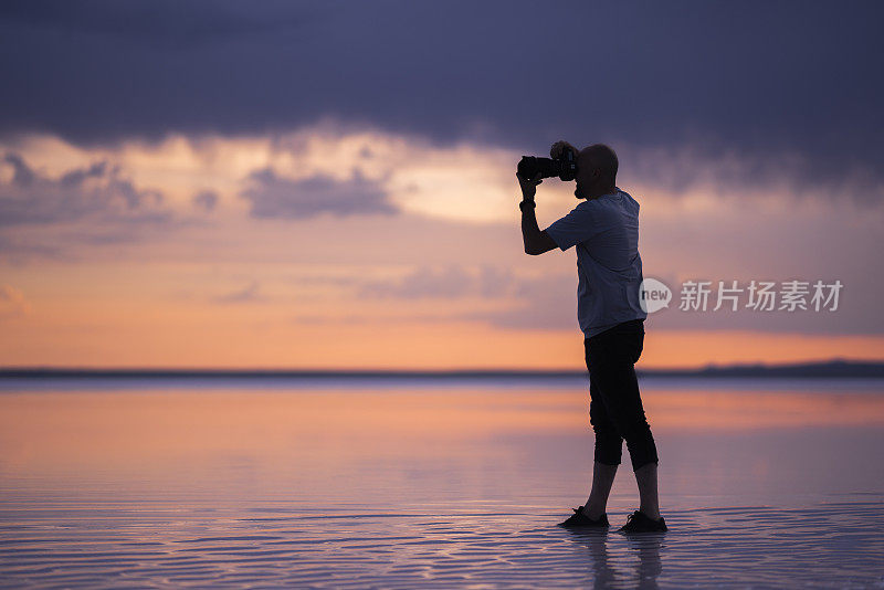 男摄影师在海边拍照的剪影