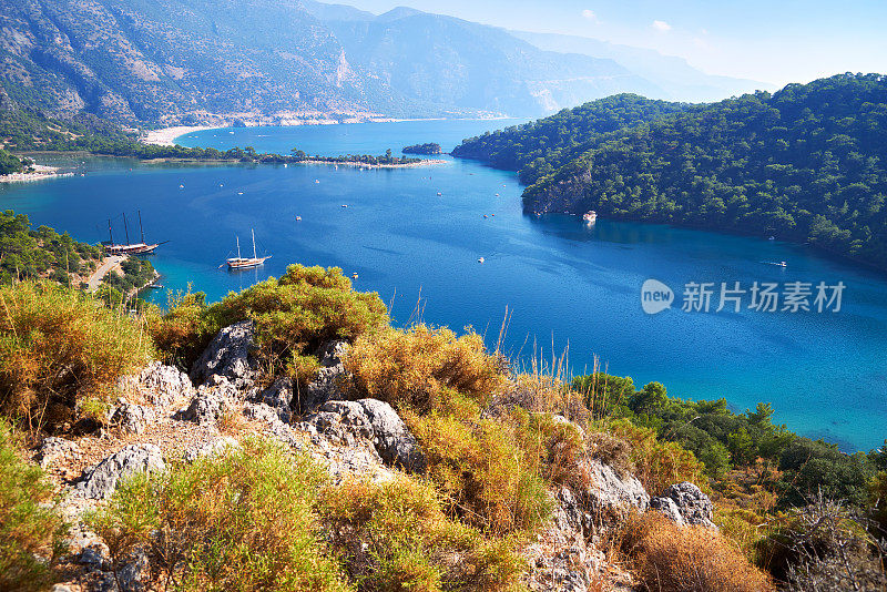 从山上看到土耳其Fethiye附近的Oludeniz泻湖的蓝色水面。地中海沿岸树木丛生，天空晴朗