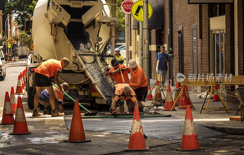 身穿橙色连衣裙的人们在新南威尔士州曼利大街上浇注混凝土
