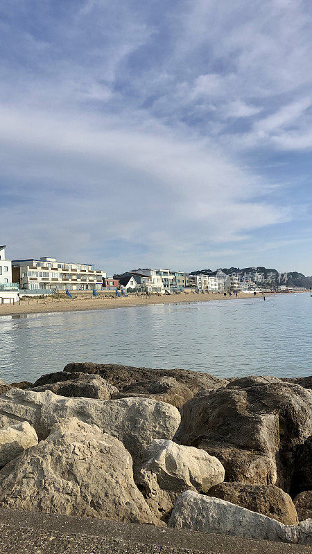 英国多塞特郡普尔海滩的沙滩岩石海防和海岸景色，平静的大海和蓝天