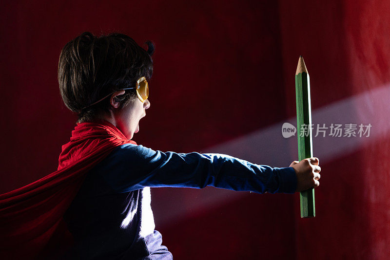 小学生穿着超级英雄服装拿着大钢笔的照片