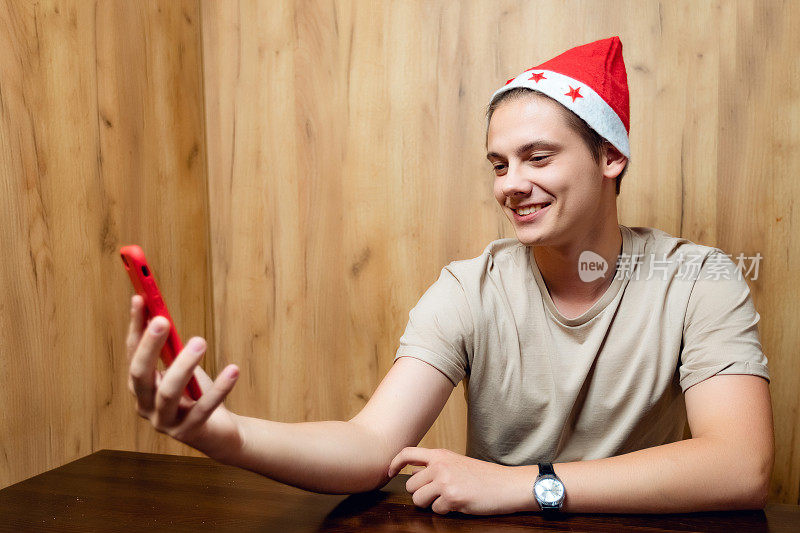 一名戴着圣诞老人帽子的男子正在使用手机。人们拿着智能手机进行视频通话和交流