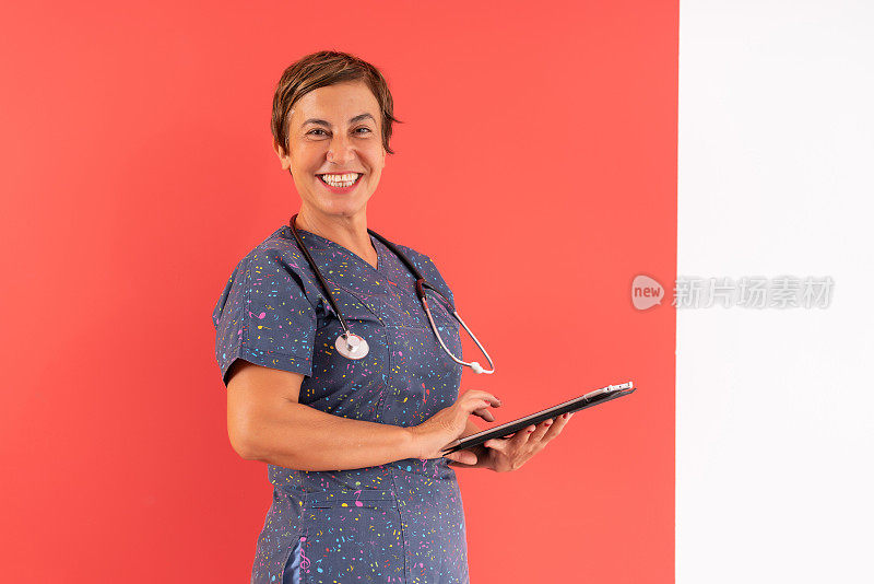 一名女医生在彩色墙上使用数码平板电脑的工作室肖像。