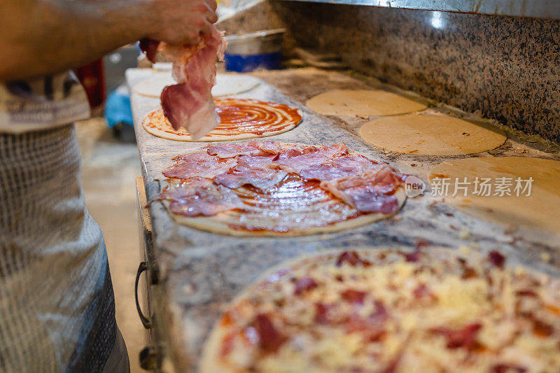 特写厨师的手，面包师在厨房做披萨。制作披萨的过程。双手准备披萨。