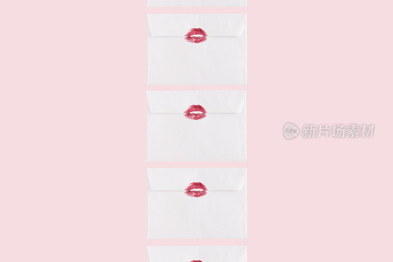 创意图案，白色信封与红色的吻。最小的爱情构成在粉红色的背景。