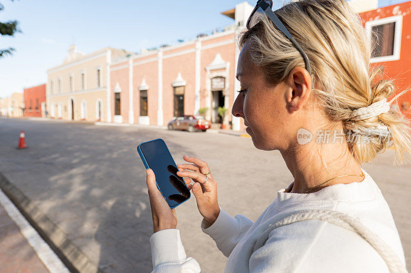 在色彩缤纷的城市里，一名年轻女子正在使用她的手机、手机应用程序和在线购物