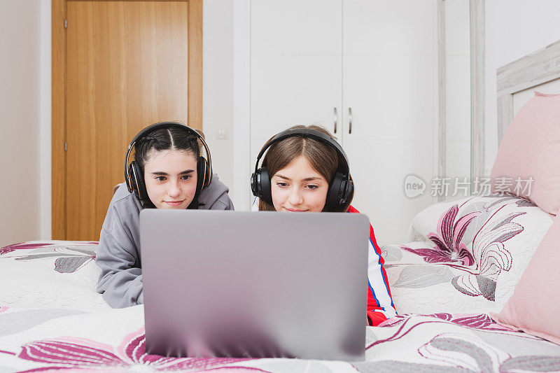 快乐的青少年朋友带着笔记本电脑在家里听音乐。