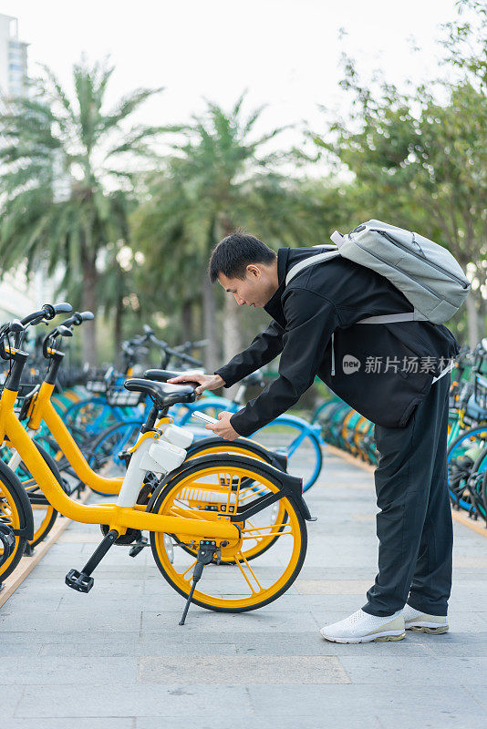 亚洲男子用智能手机扫描二维码解锁共享单车