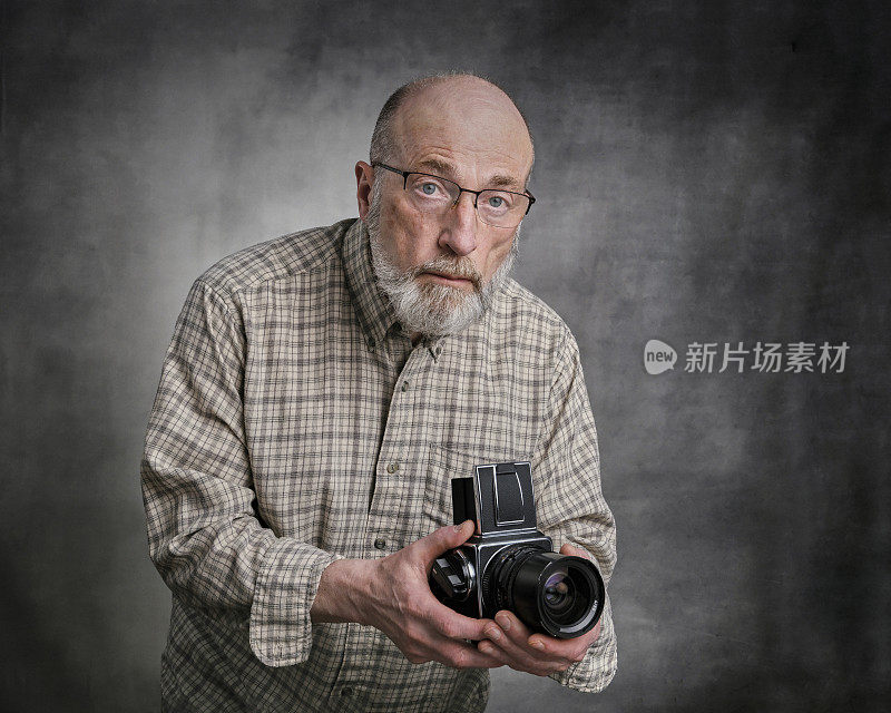 一名老年男性摄影师的肖像与旧相机