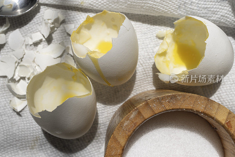 煮完煎蛋后放在厨房桌子上的打碎的鸡蛋和打开的盐瓶。