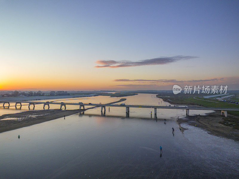 在美丽的冬日夕阳下，荷兰的湖面上滑冰