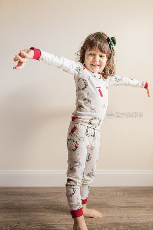 2022年12月，一个快乐而充满希望的三岁小女孩穿着简单的中性圣诞睡衣在家度过一个舒适的圣诞季