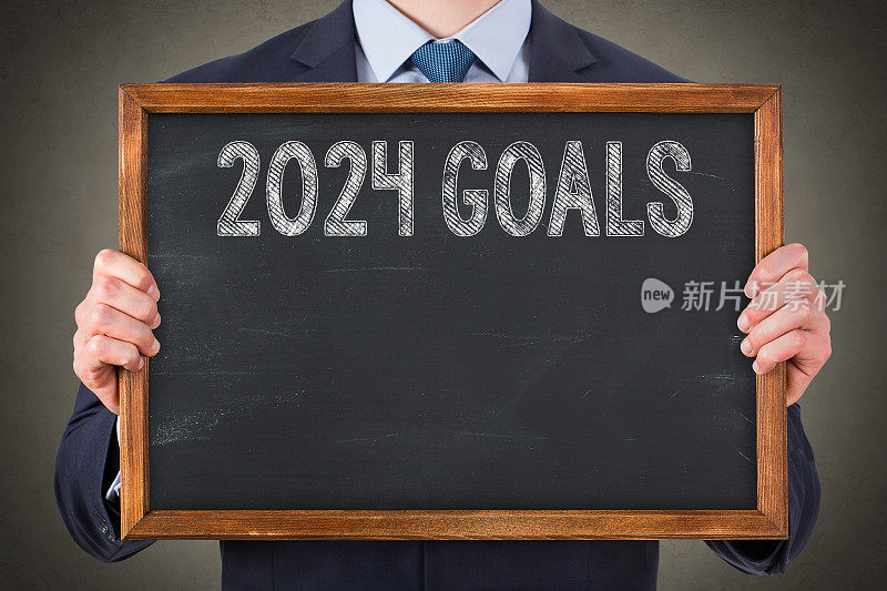 商务人士在黑板背景上写下新的2024年目标