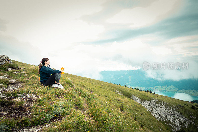 一个女人在陡峭的斜坡上休息，欣赏风景。
