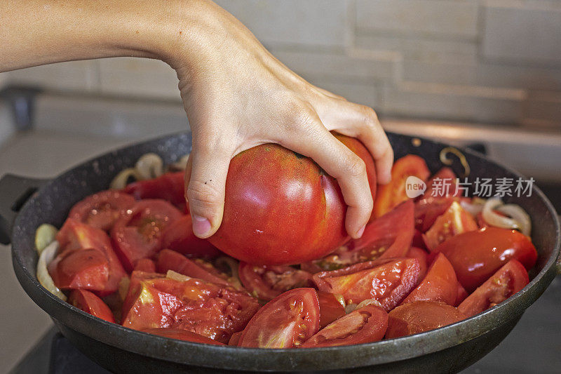 女孩用手在煎锅上拿着一个粉红色的西红柿。flatlay