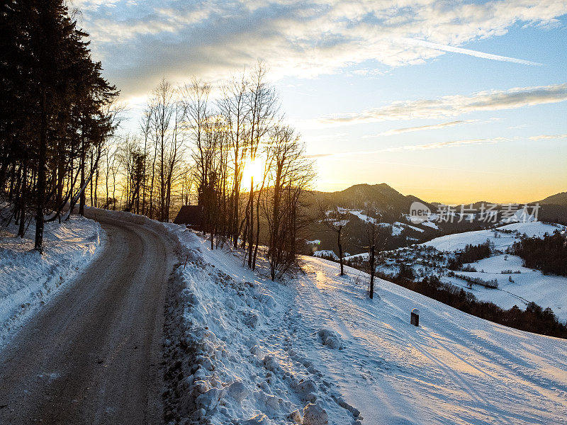 日落时的冬日道路，白雪覆盖的山丘和晴朗的天空