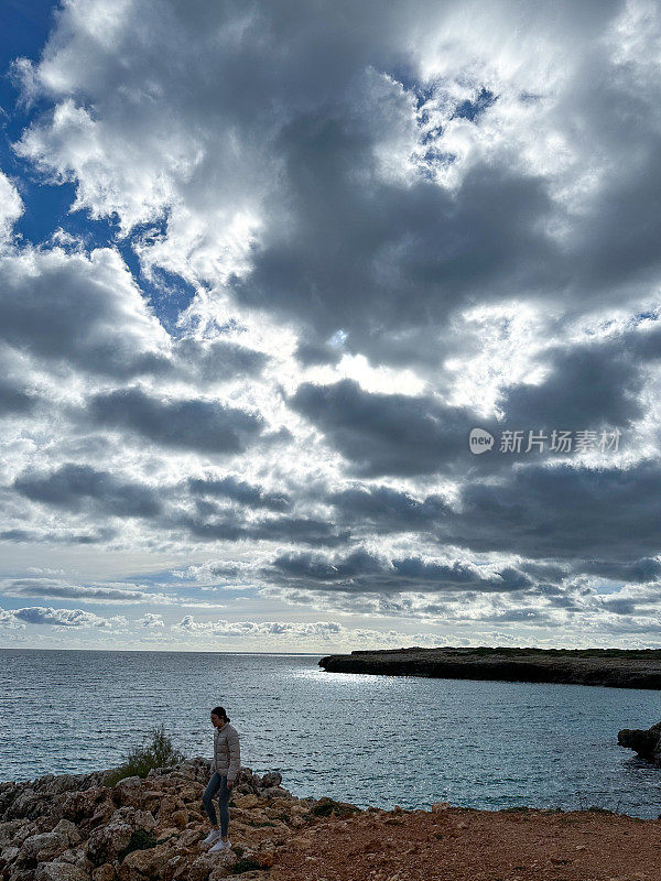 一个十几岁的女孩走在海边的悬崖上