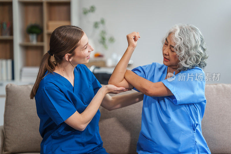 一位年轻的白人物理治疗师和一位60多岁的亚洲老年妇女参加了关于肌肉疼痛和肌肉无力的物理治疗课程。用松紧带让脚后跟疼痛