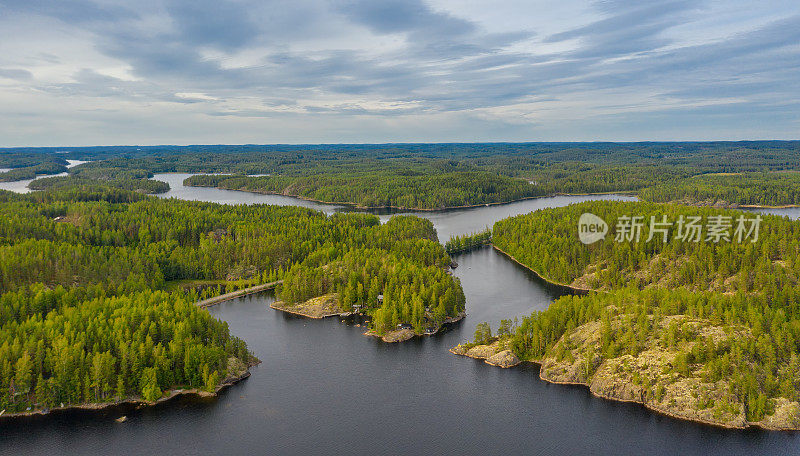 鸟瞰图上的小岛上蓝色的湖Saimaa。景观与无人机。在一个多云的夏日早晨，从空中俯瞰蓝色的湖泊、岛屿和绿色的森林。芬兰的湖泊景观。